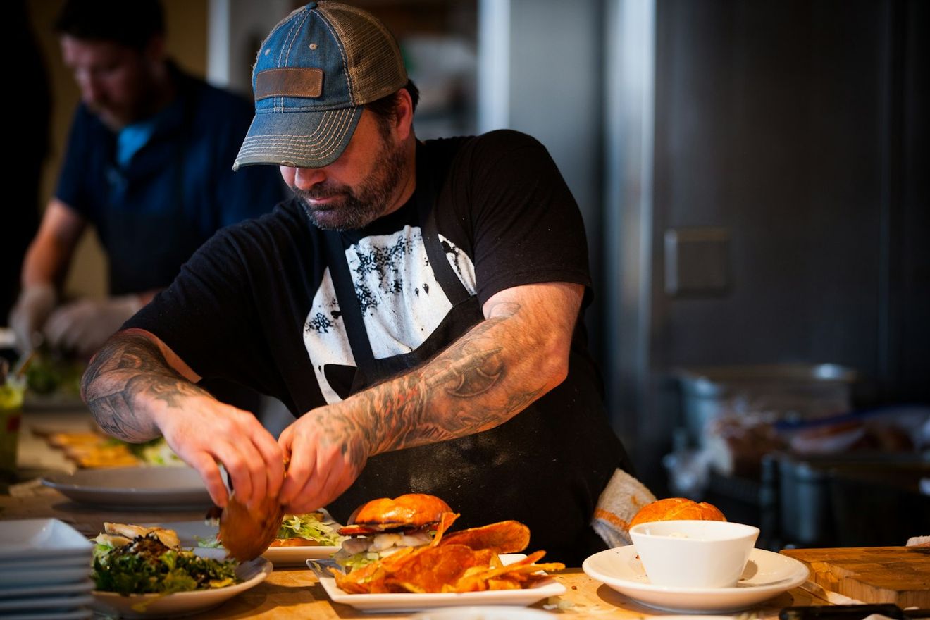 A chef finishing a plate at the kitchen pass
