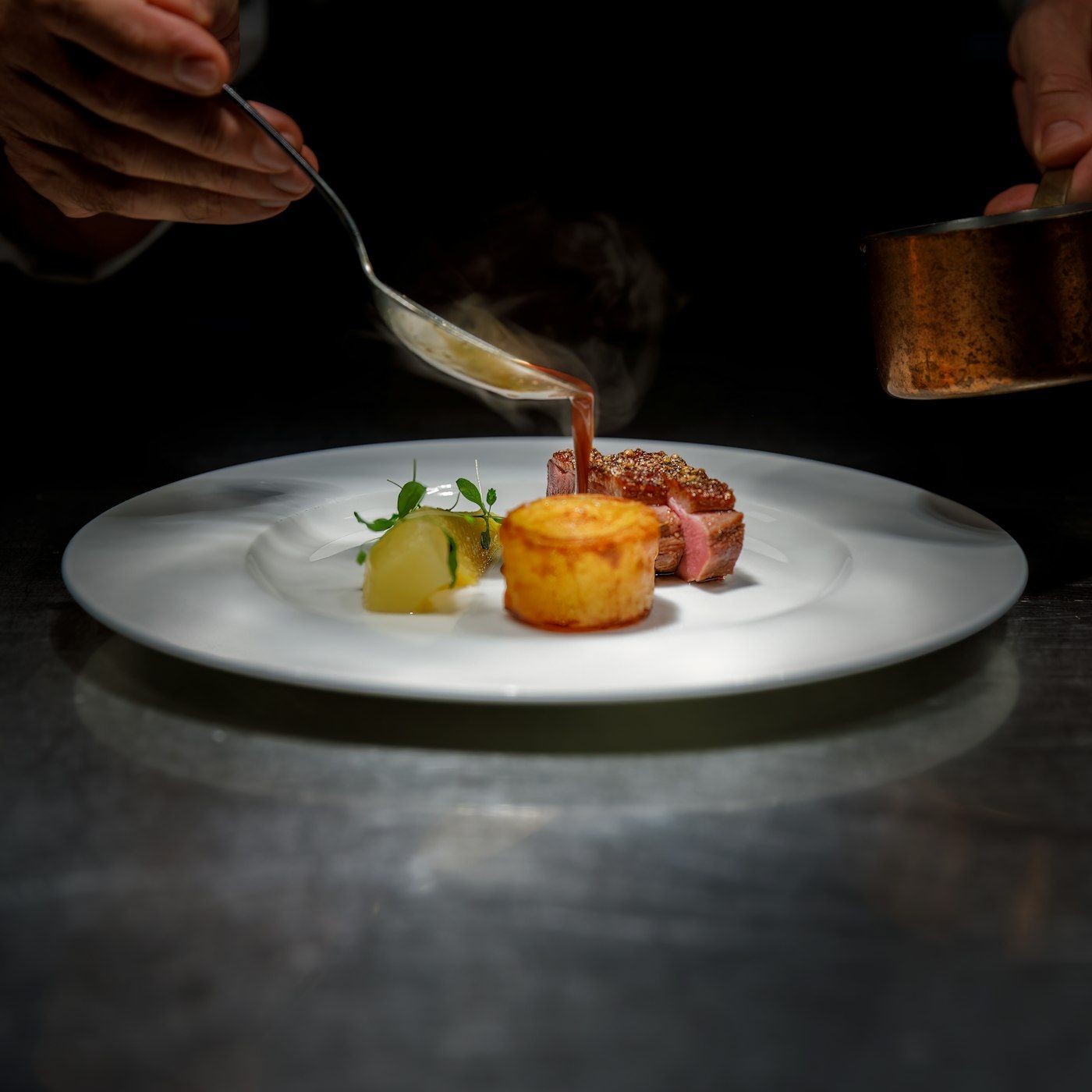 A dish plated at Ember, lit by low warm lamps before service