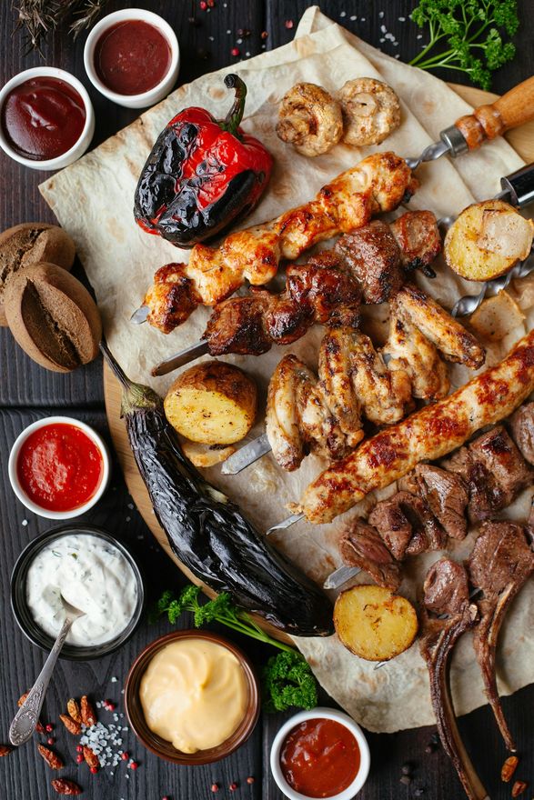 Skewers and vegetables cooking over open coals